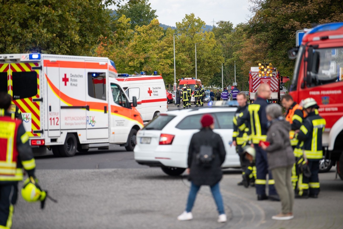 Einsatzkräfte der Feuerwehr und des Roten Kreuzes stehen nach einem Gasaustritt vor der Schule in Idstein
