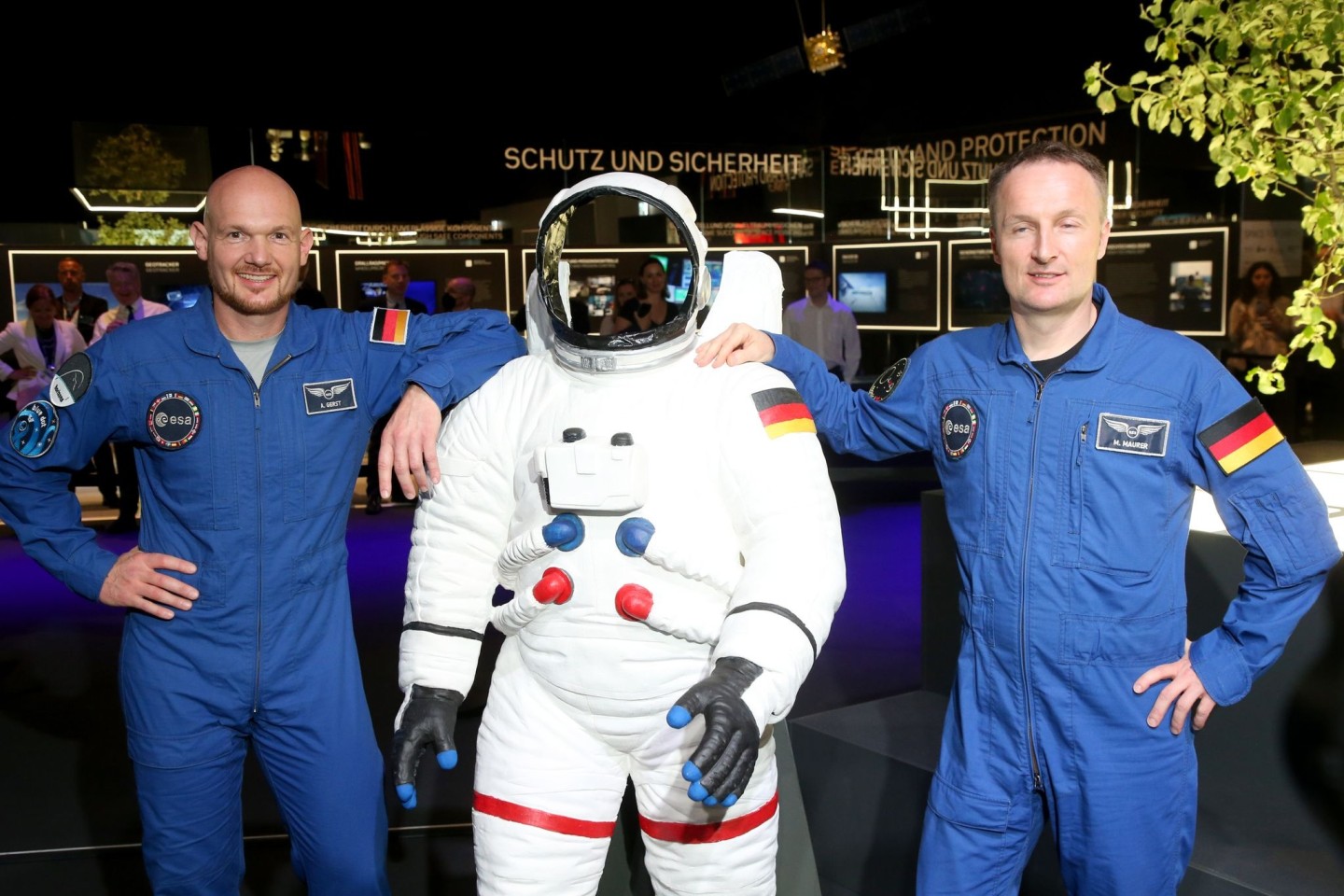 Astronaut Matthias Maurer (r) mit seinem Kollegen Alexander Gerst (l) stehen neben einer Figur mit einem Raumanzug auf der Internationalen Luft- und Raumfahrtausstellung (ILA).