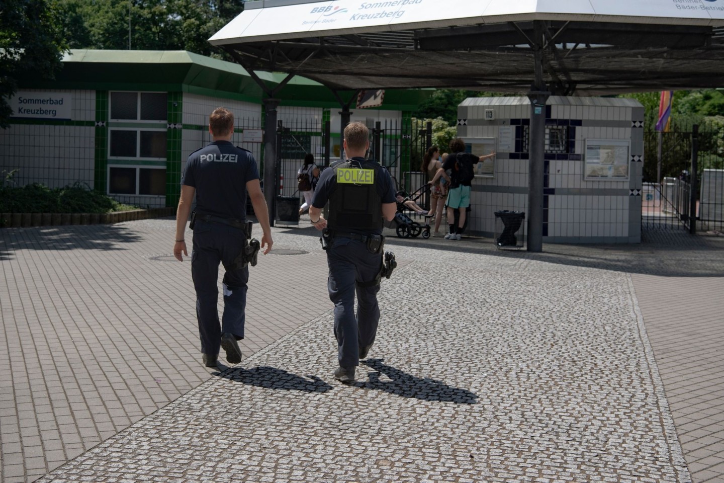 Zwei Polizsten der Mobilen Wache gehen auf das Prinzenbad in Kreuzberg zu.
