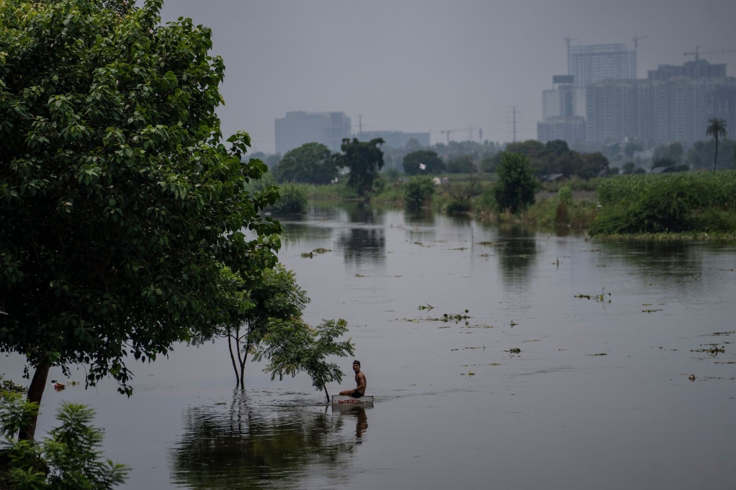 Ein Junge sitzt auf einem Schild in der Nähe einer Wohnkolonie, die vom Hochwasser des Flusses Hindon überschwemmt wurde.