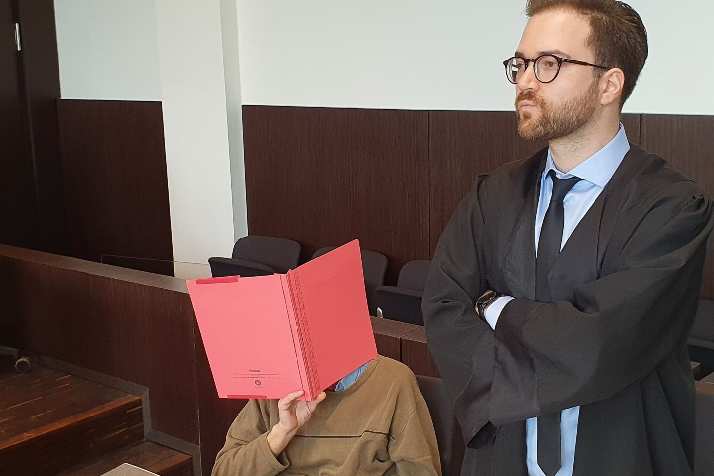 Der Angeklagte (l) sitzt neben seinem Verteidiger Maximilian Klefenz im Verhandlungssaal des Düsseldorfer Landgerichts und verdeckt sein Gesicht.