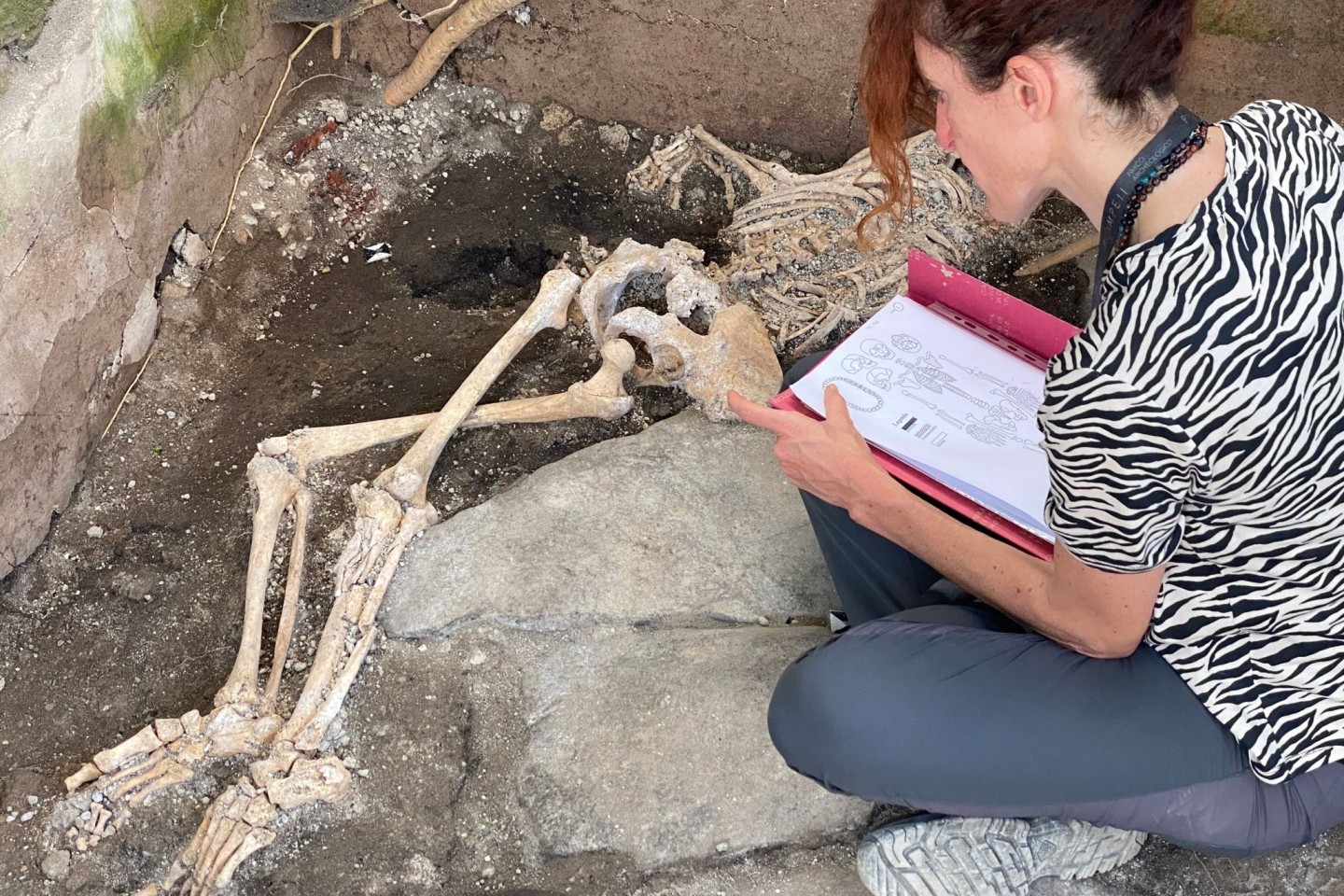 Eine Frau sitzt vor einem Skelett im Archäologiepark Pompeji.
