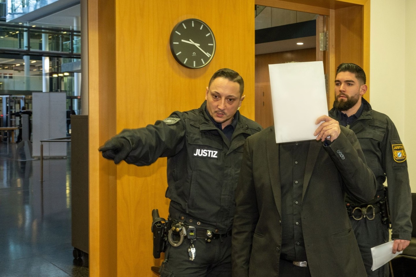 Im Strafjustizzentrum bringen zwei Justizwachtmeister einen Mann in den Sitzungssaal. Er ist zusammen mit seinem Sohn am Amtsgericht Augsburg angeklagt.