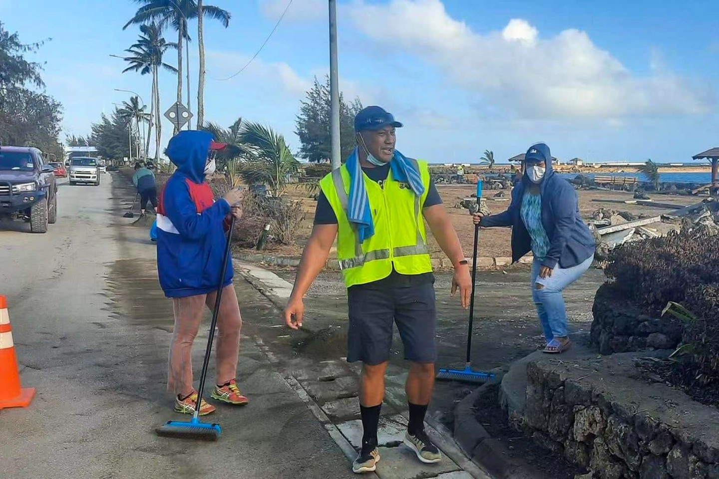 Anwohner fegen Asche von einer Straße nach dem Ausbruch eines unterseeischen Vulkans vor Tonga.