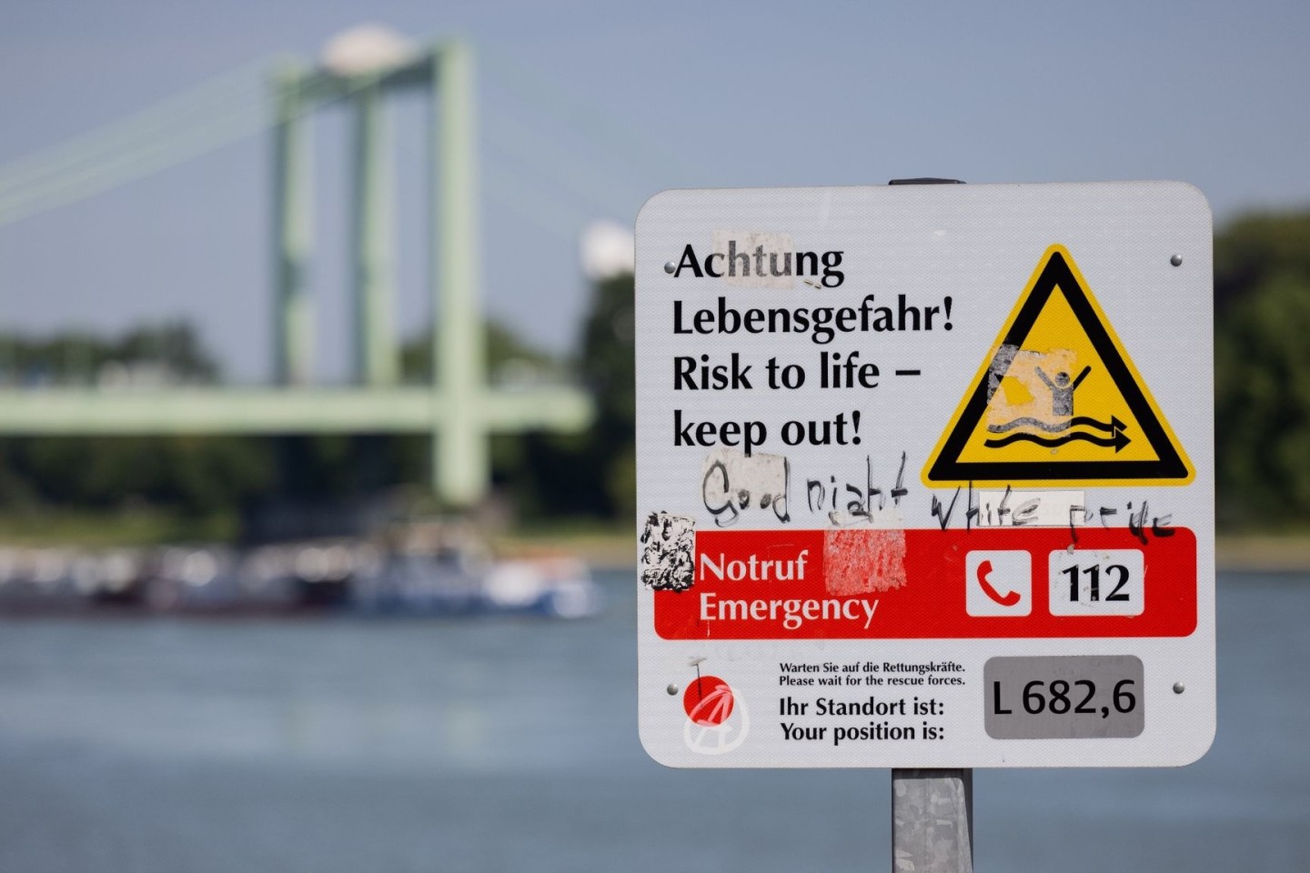 Ein Schild am Rheinufer weist auf die Gefahren beim Schwimmen im Fluss hin.