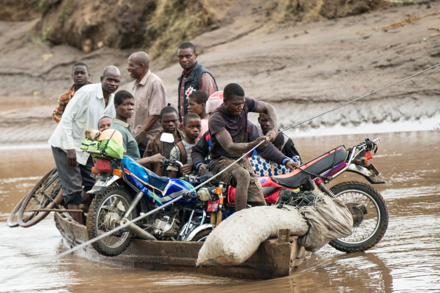 Nach dem Zyklon transportieren Männer in Malawi ihre geretteten Habseligkeiten mit einem Holzboot.