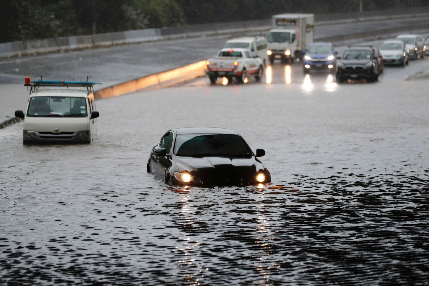 Fahrzeuge stehen im Hochwasser einer überschwemmten Straße im neuseeländischen Auckland.