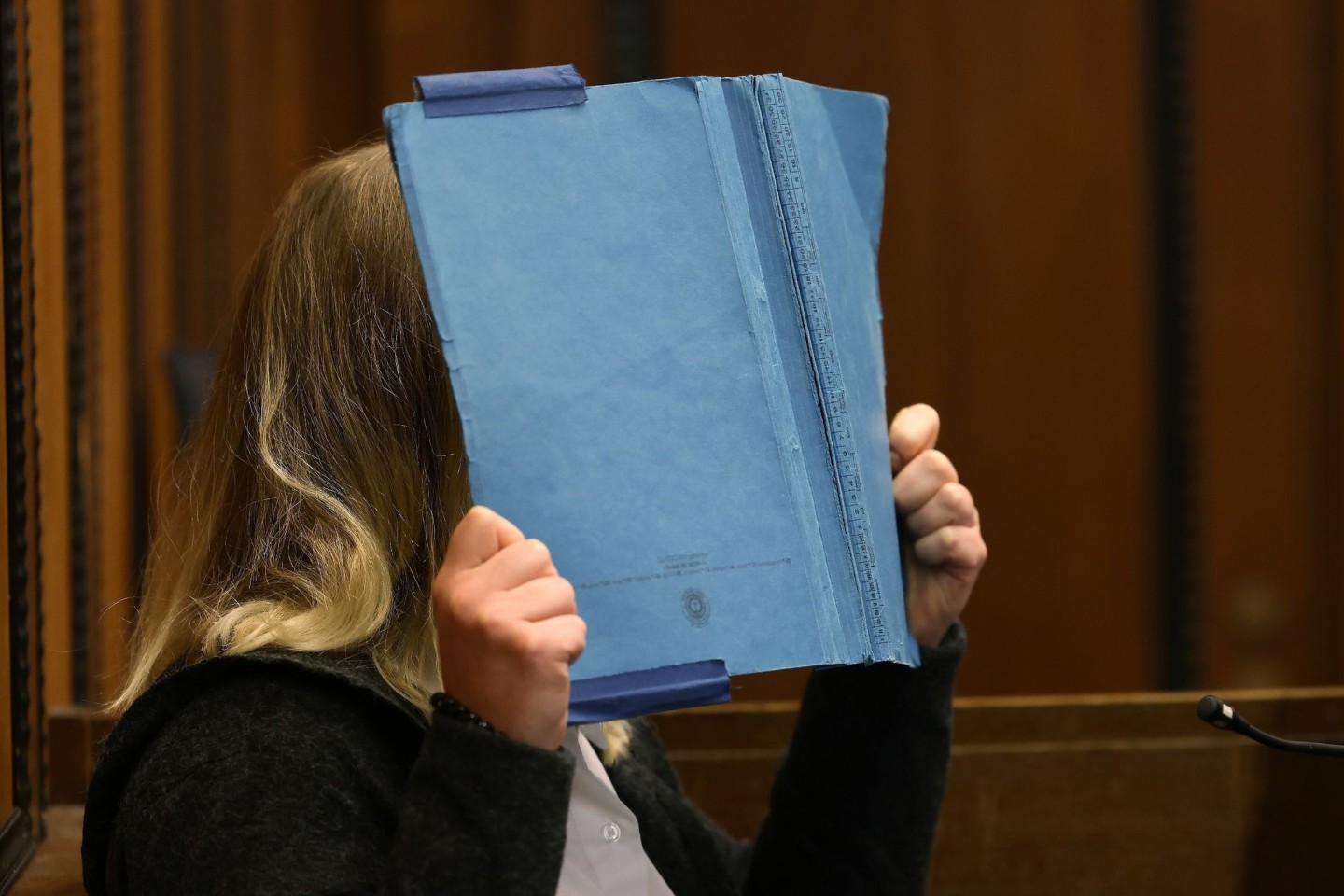 Die Angeklagte deckt im Landgericht ihr Gesicht mit einem blauen Ordner ab. Rund acht Monate nach der Entdeckung eines getöteten Babys in Mönchengladbach beginnt der Prozess gegen die Mutt...