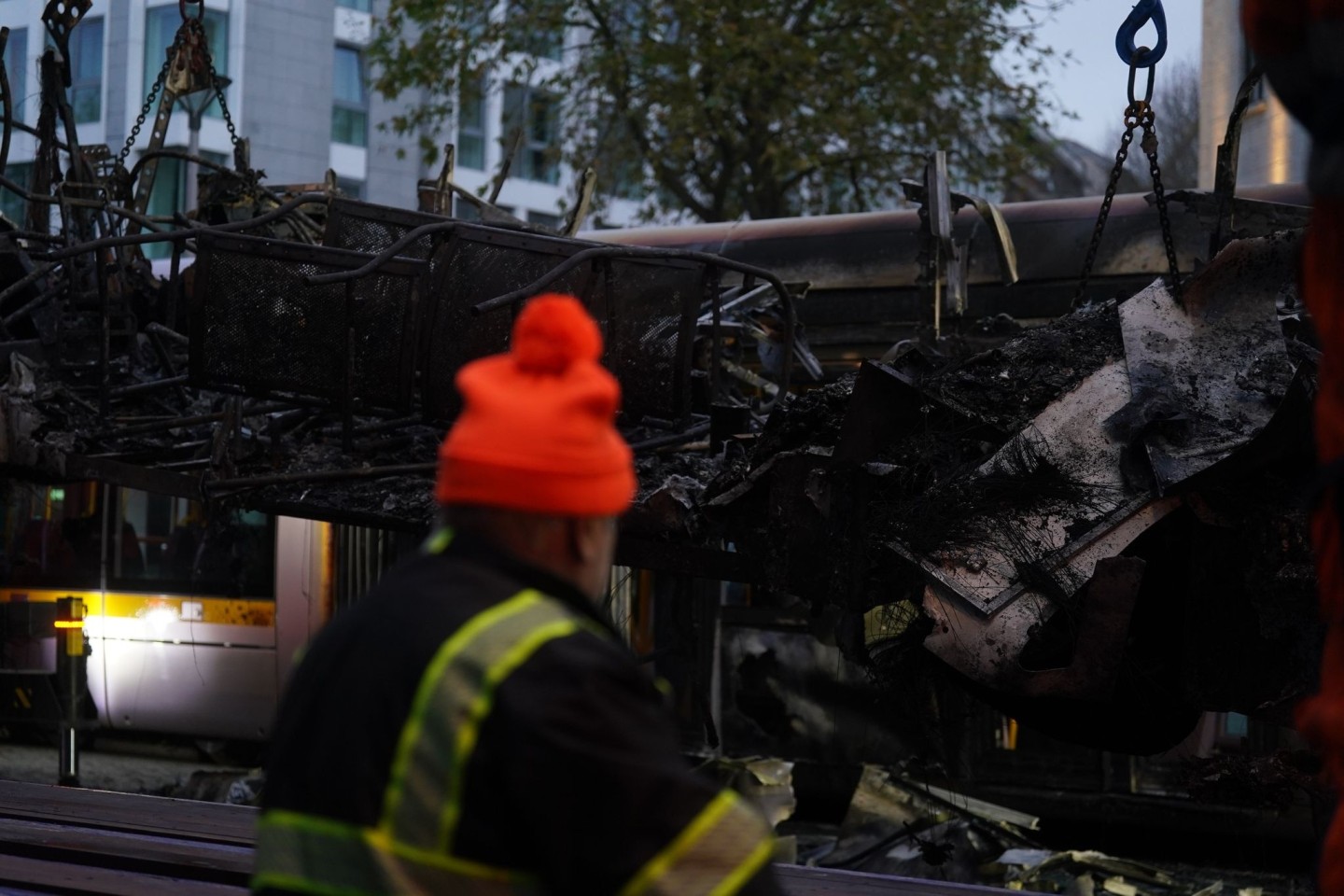 Spuren der Ausschreitungen in Dublin. Ein Arbeiter steht vor einer ausgebrannten Straßenbahn.