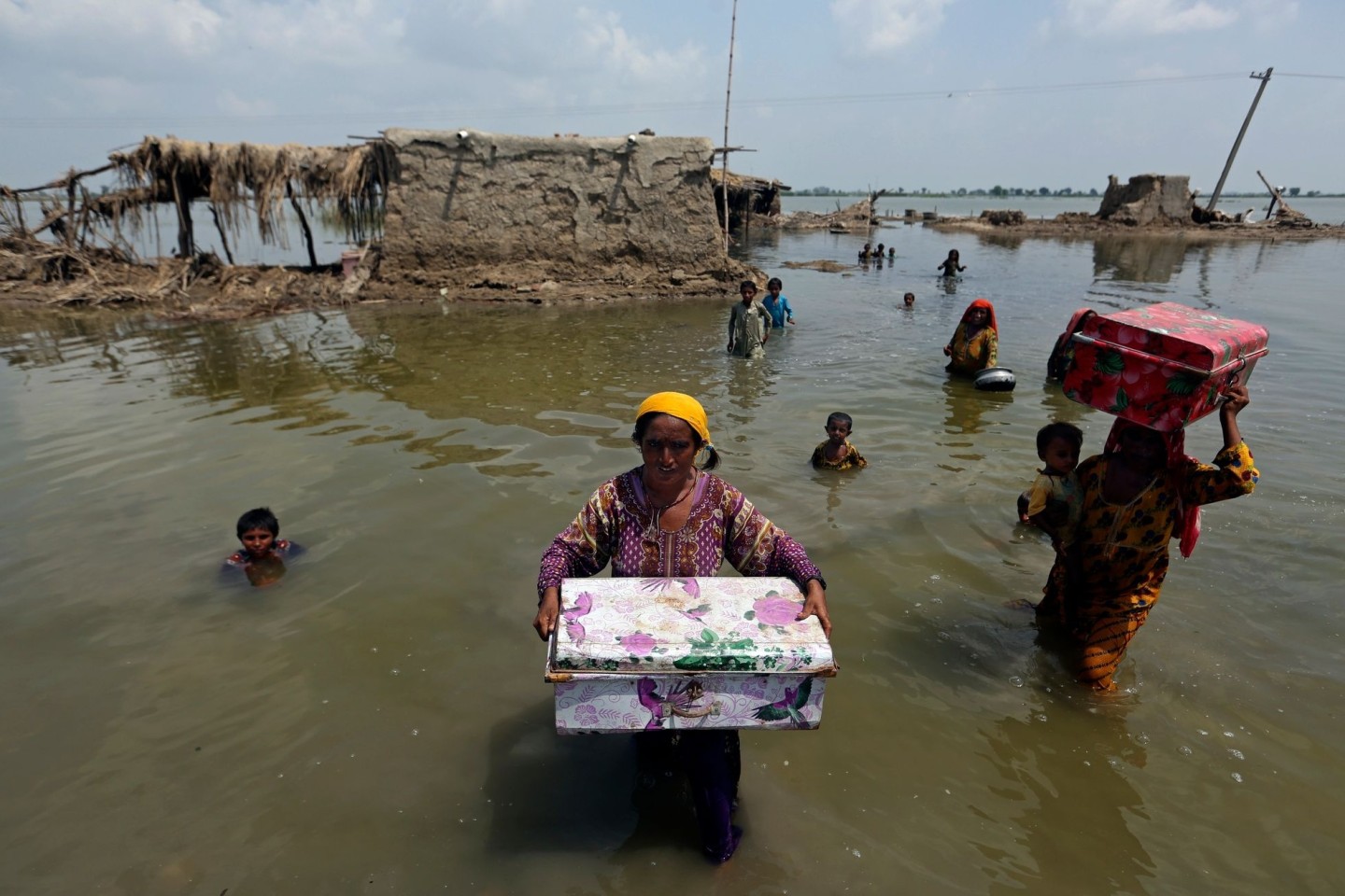 Frauen tragen Habseligkeiten aus ihrem durch heftige Regenfälle überschwemmten Haus im Bezirk Qambar Shahdadkot in der pakistanischen Provinz Sindh.