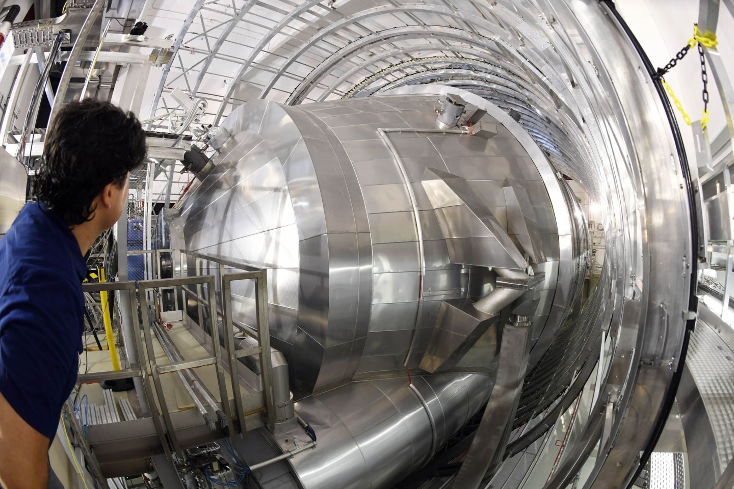 Ein Mitarbeiter des Karlsruher Tritium Neutrino Experiments (Katrin) am Karlsruher Institut für Technologie (KIT) blickt auf das Hauptspektrometer der Anlage. Mit dem Experiment soll die Ma...