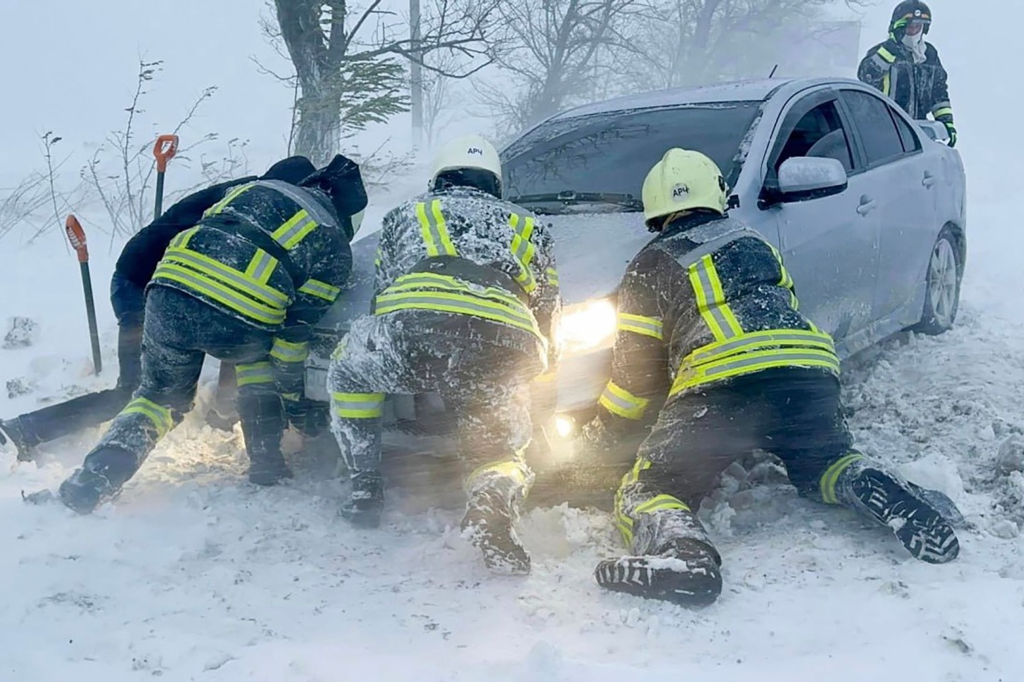 Ukrainische Rettungskräfte versuchen, ein im Schnee steckengebliebenes Auto auf der Autobahn in der Region Odessa zu bergen.